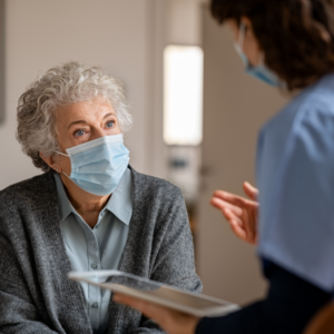 Senior woman wearing a mask while talking to the doctor