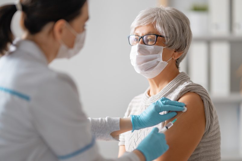 Doctor giving elderly woman a vaccine in arm