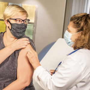 Woman getting vaccination from doctor in her arm