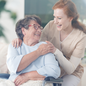 Smiling senior in wheelchair looking up at caregiver